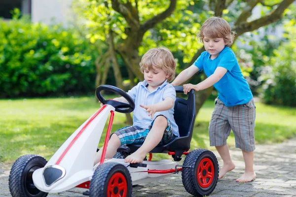 Two happy sibling boys having fun with toy car — Stock Photo, Image