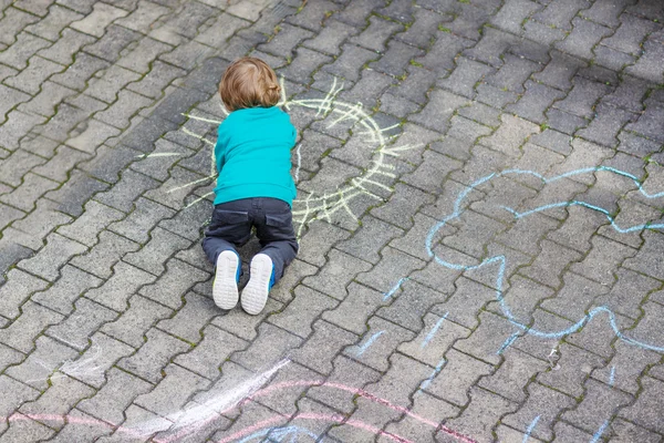 Kleine blonde jongen schilderen met kleurrijke krijtjes buitenshuis — Stockfoto