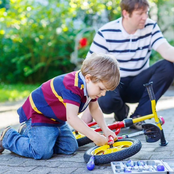 Padre enseñando a dos niños a reparar cadenas en bicicletas — Foto de Stock