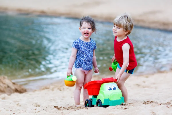 Kleine peuter jongen en meisje spelen samen met zand speelgoed in de buurt van — Stockfoto