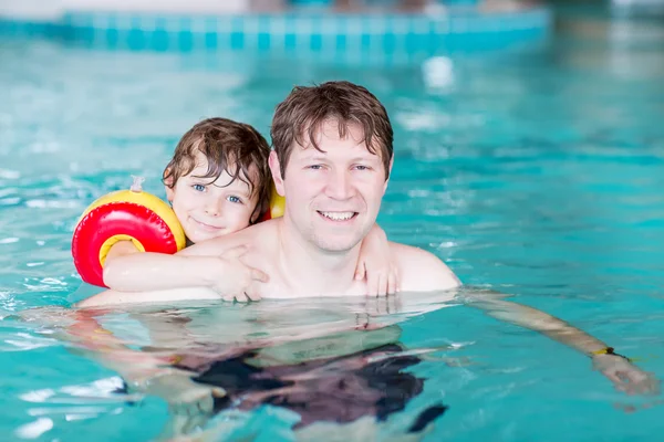 Young dad teaching his little son to swim indoors — Stock Photo, Image