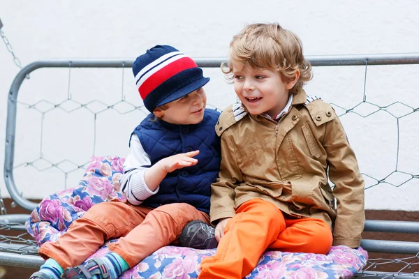 Two happy boys on hollywood swing in spring garden — Stock Photo, Image