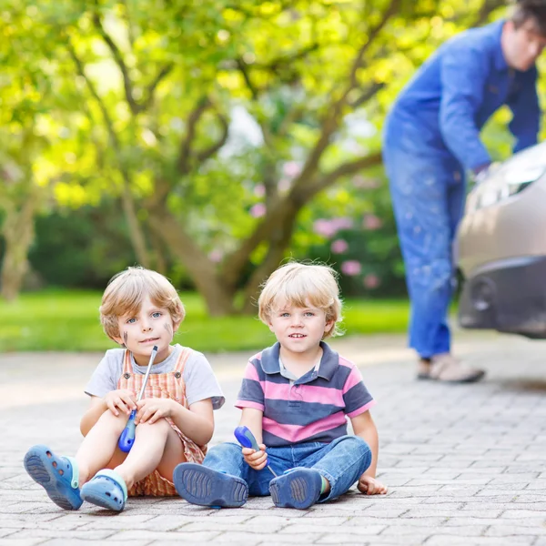 Zwei kleine Geschwister in orangefarbener Warnweste beim Vater — Stockfoto