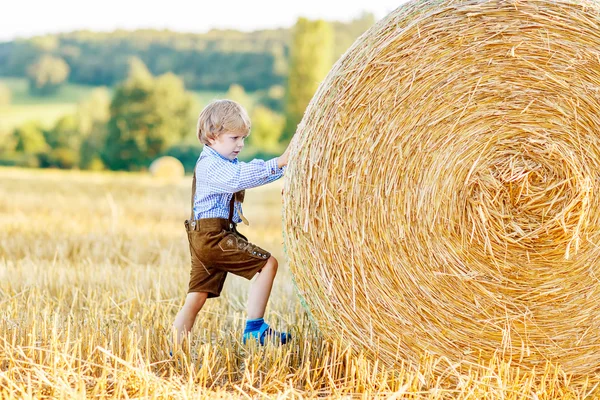 Sevimli küçük çocuk çocuk saman yığını ile eğleniyor buğday sahada — Stok fotoğraf