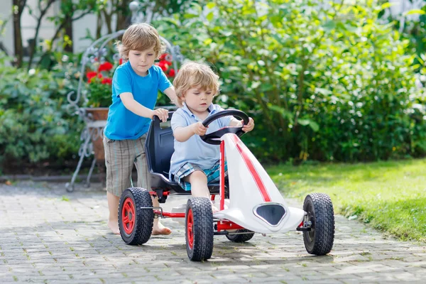 Due bambini felici si divertono con la macchina giocattolo — Foto Stock