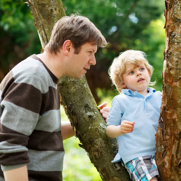 Cute little kid boy enjoying climbing on tree with father, outdo — Stock Photo, Image