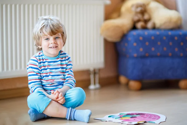 Piccolo ragazzo biondo carino che gioca con puzzle game a casa — Foto Stock