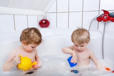 Eğleniyor ve bathtu alarak banyoda tarafından su ile oynarken İkizler