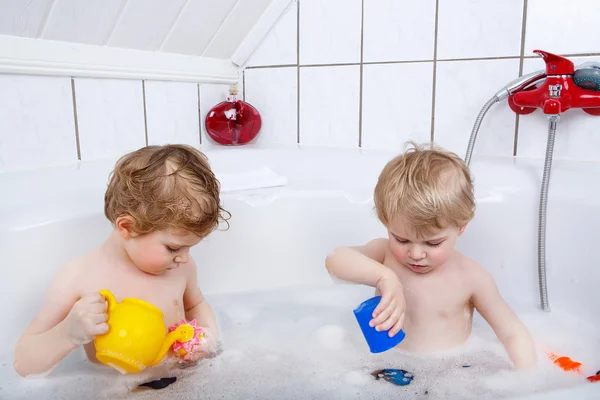 Zwillinge haben Spaß und spielen mit Wasser, indem sie in bathtu baden — Stockfoto