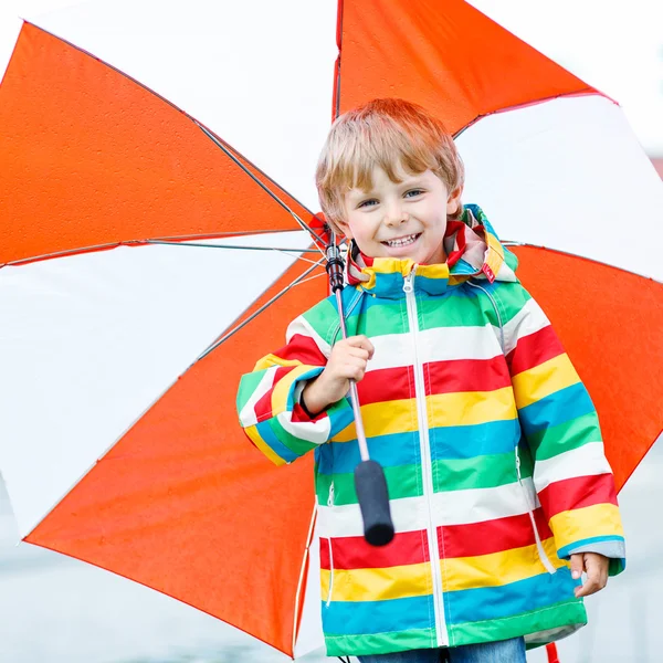 Pequeño niño rubio caminando con un gran paraguas al aire libre — Foto de Stock