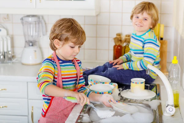Dwóch chłopców mały blond bliźniaki mycie naczyń w domowej kuchni — Zdjęcie stockowe