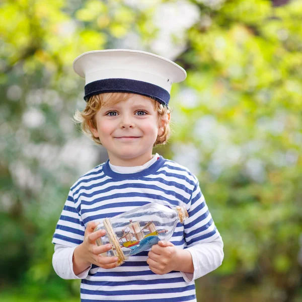 Criança feliz em uniforme de capitão brincando com navio de brinquedo — Fotografia de Stock