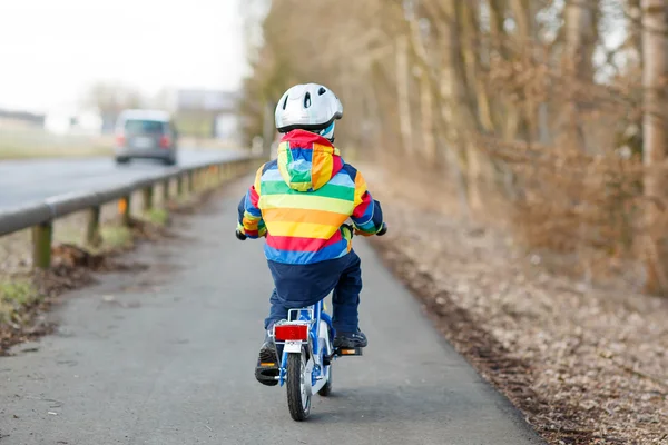 Junge mit Schutzhelm und buntem Regenmantel auf Fahrrad, Outfit — Stockfoto