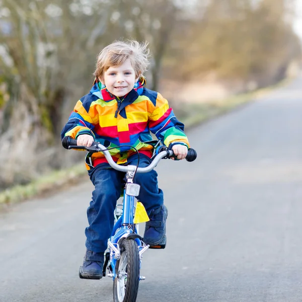 Dziecko, chłopiec w kask i kolorowy płaszcz jazda rowerem, bas — Zdjęcie stockowe