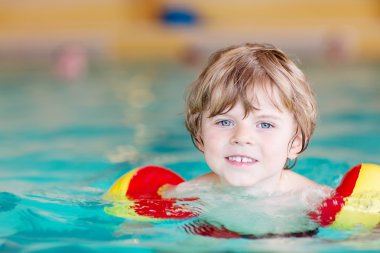 küçük çocuk çocuk swimmies bir kapalı havuzda yüzmek için öğrenme ile