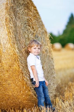 Sevimli sarışın küçük çocuk çocuk saman sahada eğleniyor