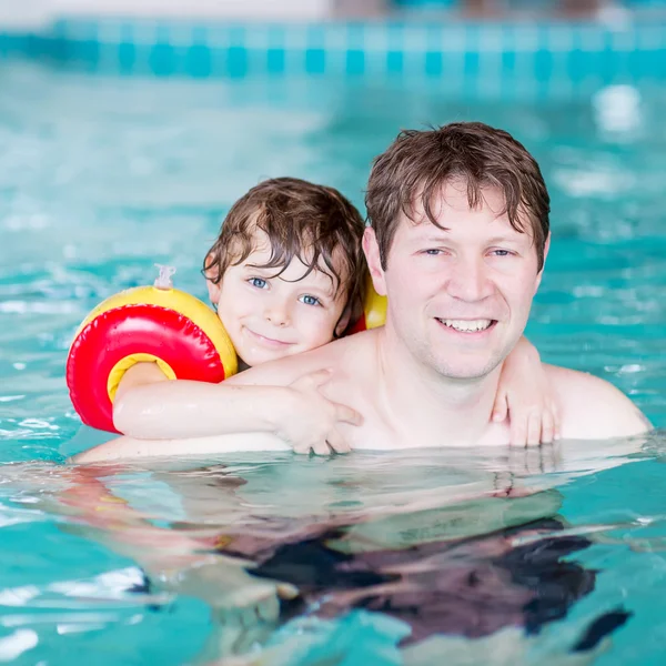 Young dad teaching his little son to swim indoors — Stock Photo, Image