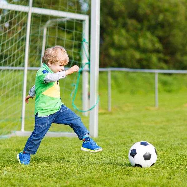 Two little sibling boys playing soccer and football on field — Stock Photo, Image