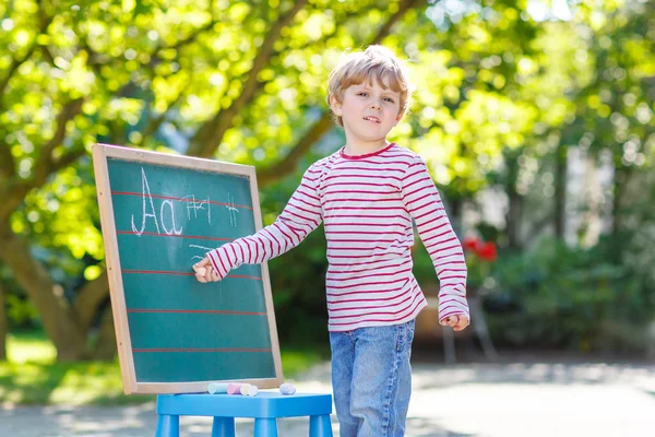 Liten pojke på blackboard lära sig att skriva — Stockfoto
