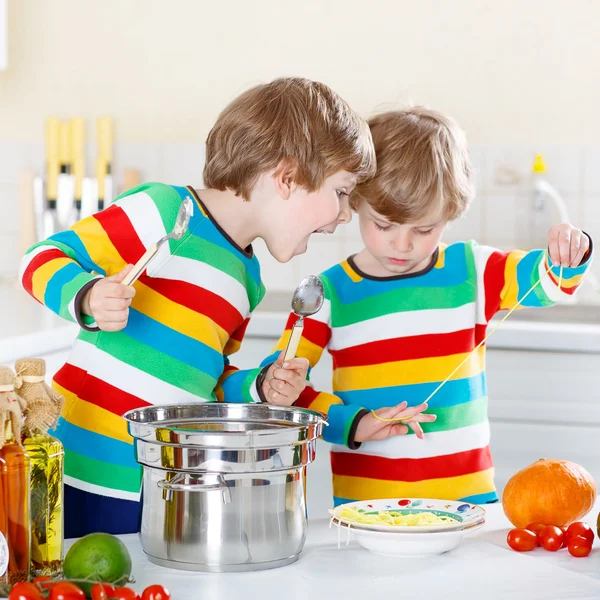 Two little kid boys eating spaghetti in domestic kitchen. — Stock Photo, Image