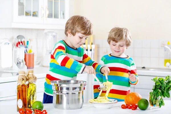 Dwa małe dziecko chłopców jedzenie spaghetti w domowej kuchni. — Zdjęcie stockowe