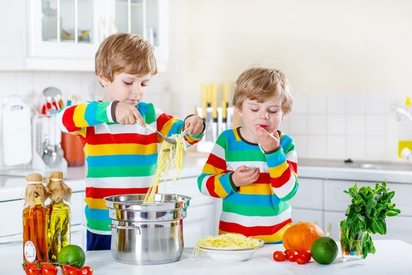 Dois meninos pequenos comendo espaguete na cozinha doméstica . — Fotografia de Stock