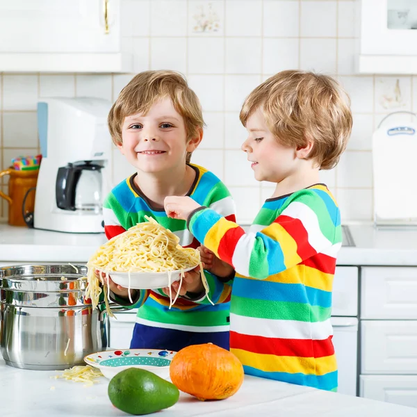 Dwa małe dziecko chłopców jedzenie spaghetti w domowej kuchni. — Zdjęcie stockowe