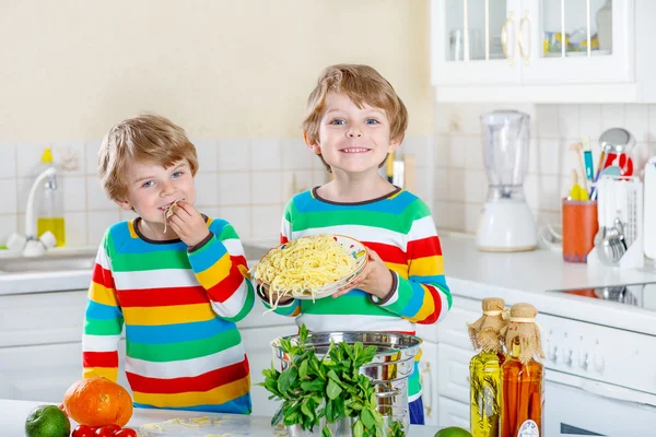 Zwei kleine Jungen essen Spaghetti in der heimischen Küche. — Stockfoto