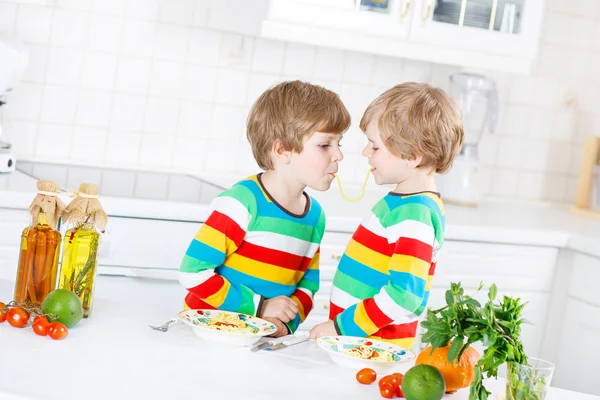 Twee kid weinig jongens eten spaghetti in binnenlandse keuken. — Stockfoto