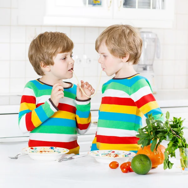 Twee kid weinig jongens eten spaghetti in binnenlandse keuken. — Stockfoto