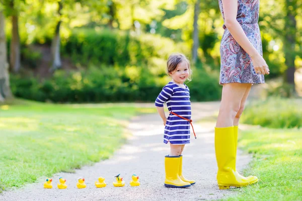 Мати і маленька чарівна дитина в жовтих гумових чоботях — стокове фото