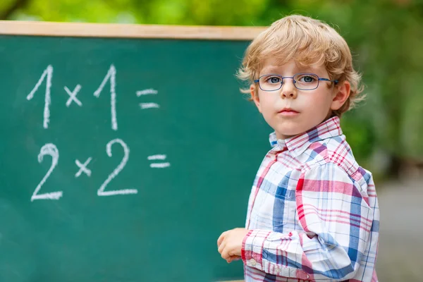 Niño preescolar con gafas en pizarra practicando matemáticas —  Fotos de Stock