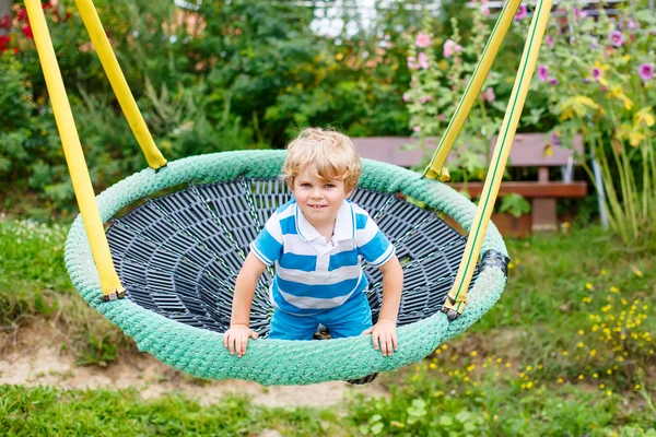 Roztomilé batole chlapce baví řetězce swing na venkovní playgroun — Stock fotografie