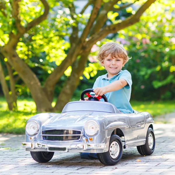 Niño pequeño conduciendo juguete grande coche viejo, al aire libre — Foto de Stock