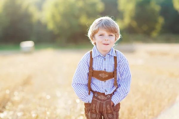 Happy blond boy walking through golden wheat field — Stock Photo, Image