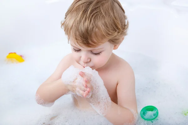 Precioso niño salpicando y jugando con espuma —  Fotos de Stock