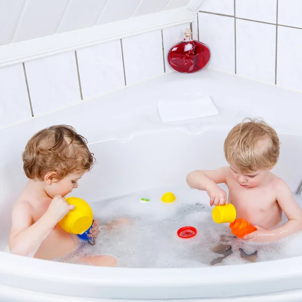 Dois meninos irmãos se divertindo com a água tomando banho em — Fotografia de Stock