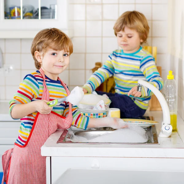 Dos divertidos amiguitos lavando platos en la cocina doméstica —  Fotos de Stock