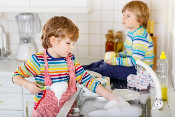 Two little blond kid boys washing dishes in domestic kitchen — Stock Photo, Image