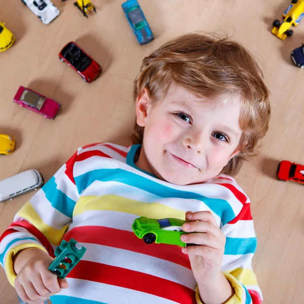 Adorabile bambino carino con un sacco di diverse auto giocattolo colorate — Foto Stock