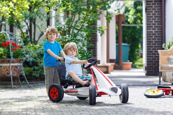 Dos niños felices hermanos divirtiéndose con coche de juguete — Foto de Stock