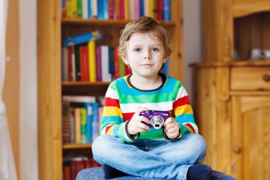 Little kid boy holding photocamera, indoors
