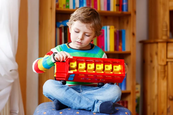 Niño rubio jugando con el autobús de juguete de madera, en el interior —  Fotos de Stock