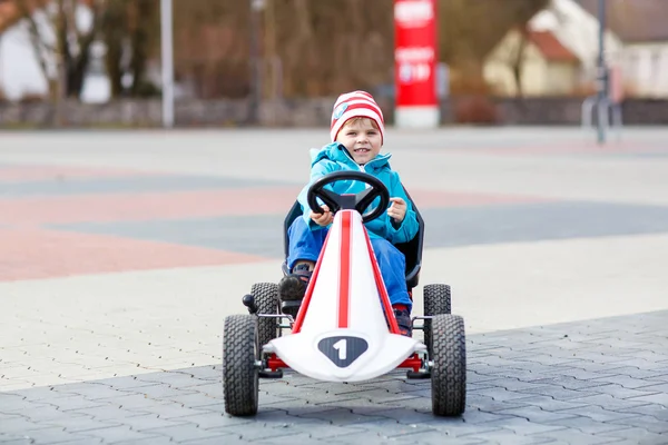 Chico lindo activo que se divierte con coches de carreras de juguete — Foto de Stock