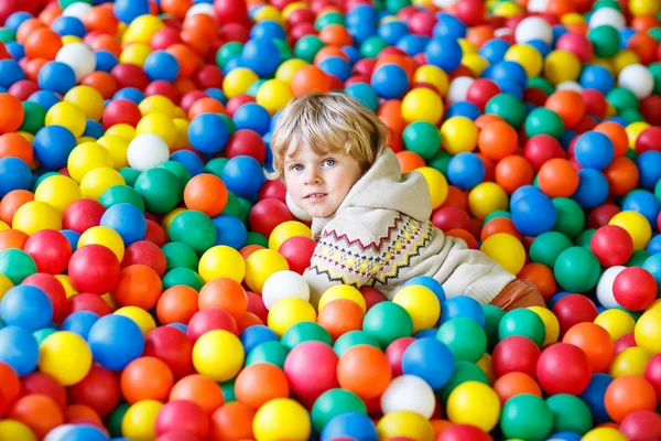 Kind spielt auf Spielplatz mit bunten Plastikbällen — Stockfoto