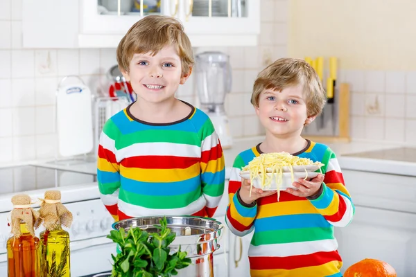 Dos niños comiendo espaguetis en la cocina doméstica . —  Fotos de Stock