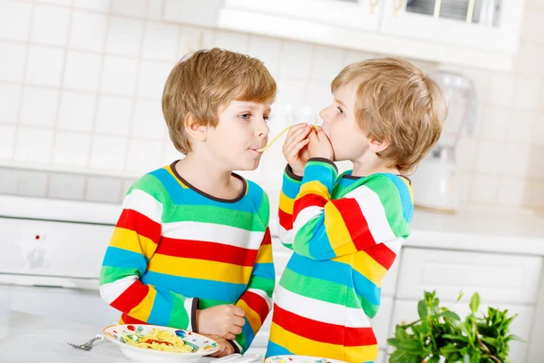 Two little kid boys eating spaghetti in domestic kitchen. — Stock Photo, Image