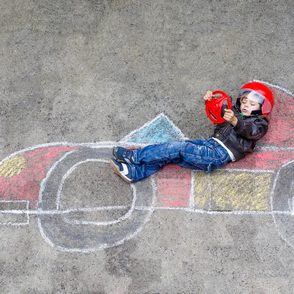 Lille pojken roar sig med racerbil rita med kritor — Stockfoto
