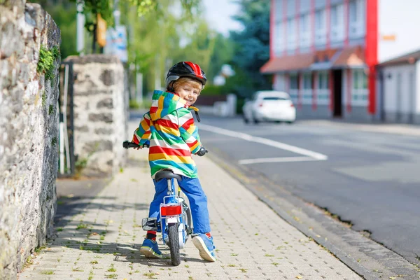 Kid boy in helmet riding his first bike, outdoors — Stock Photo, Image