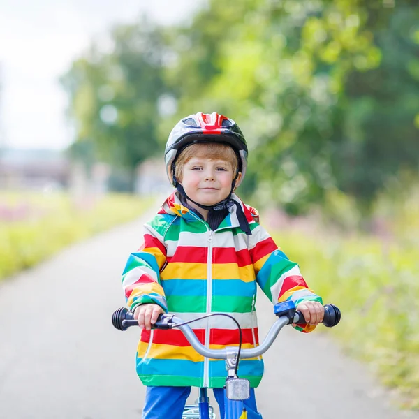 Garoto no capacete montando sua primeira bicicleta, ao ar livre — Fotografia de Stock